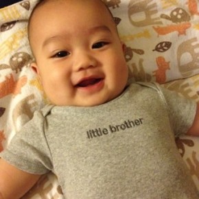 Charlie in a bodysuit that reads "Little Brother"